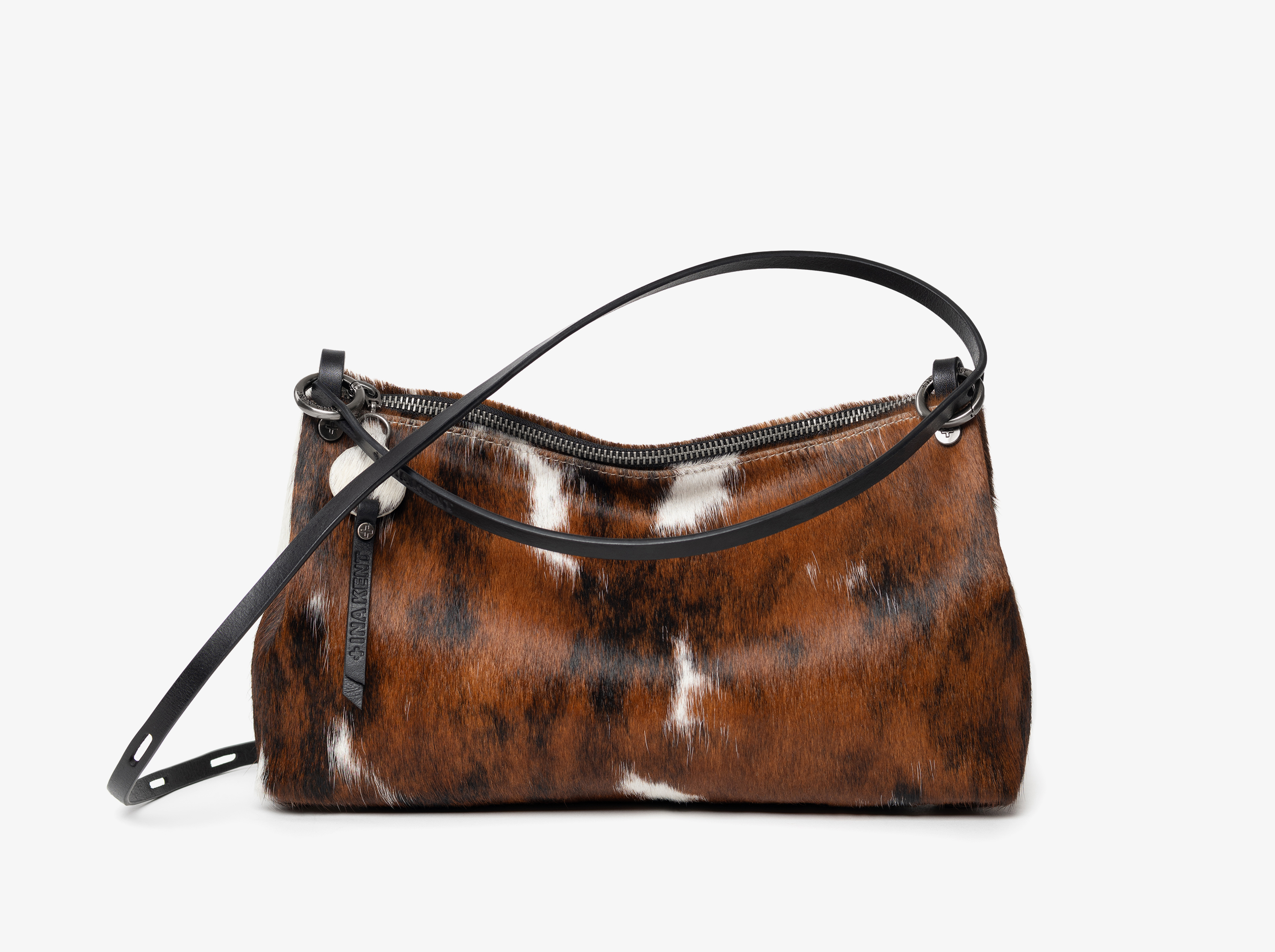 Brown and white cowhide handbag with black leather strap and zipper, displayed on a plain white background.