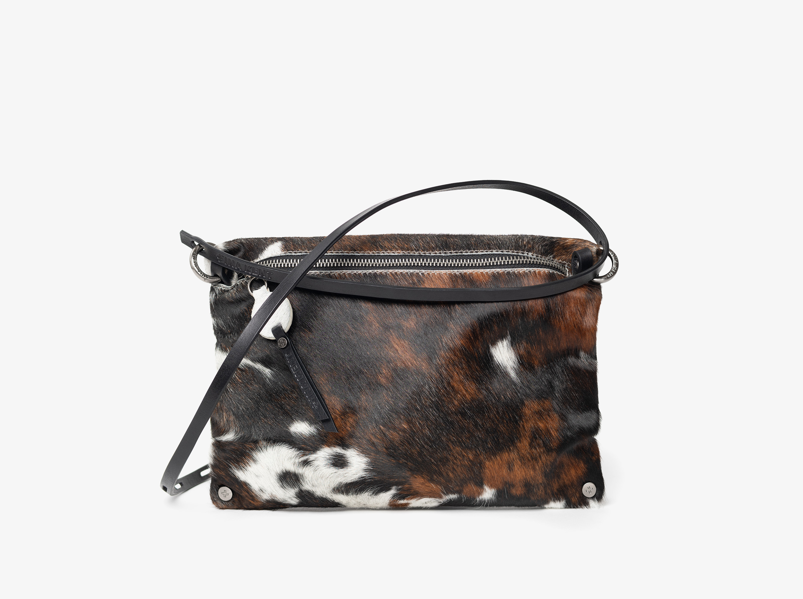 Rectangular crossbody bag with black, brown, and white cowhide pattern, a top zipper, and a black leather strap, displayed against a plain white background.