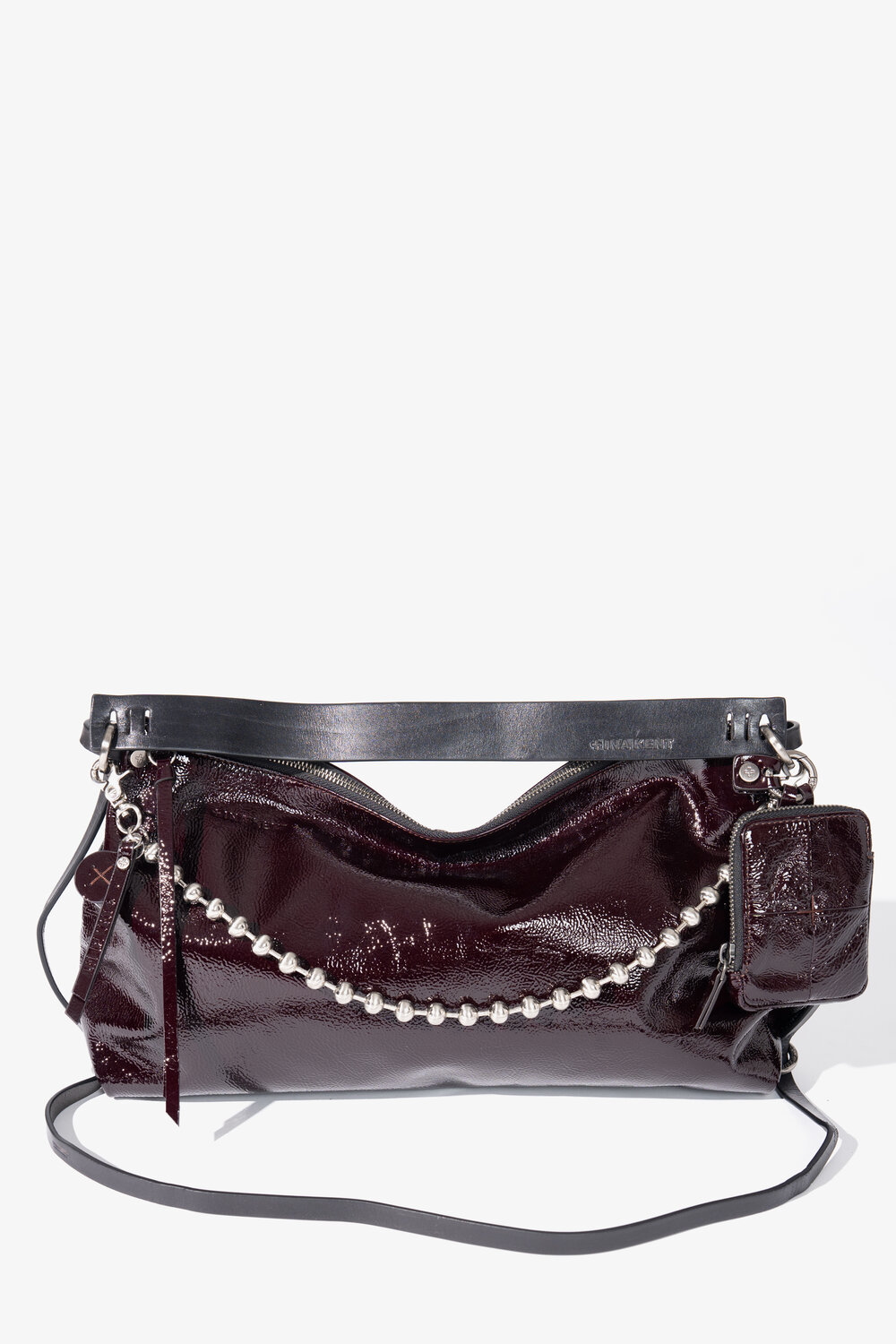 Eine dunkelburgunderrote INA KENT-Handtasche aus Lackleder mit silbernem Kettenelement, schwarzem Trageriemen und einem kleinen, daran befestigten Beutel, präsentiert vor einem schlichten weißen Hintergrund.