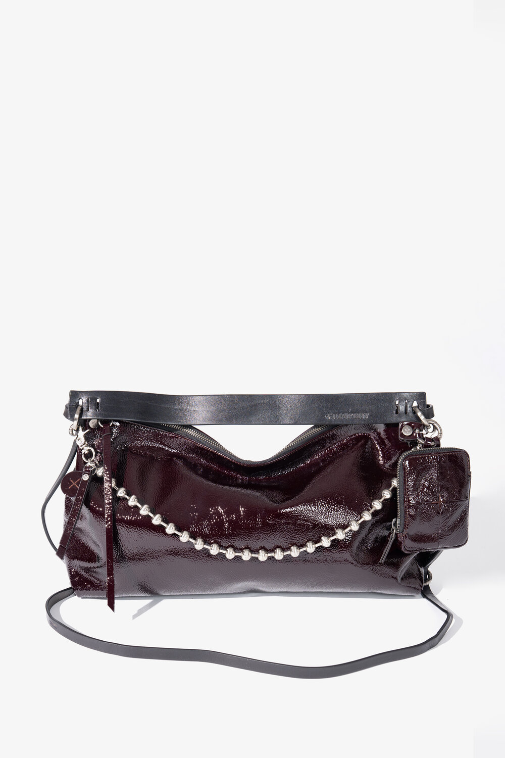 Eine glänzende, dunkelburgunderrote INA KENT-Handtasche mit silbernen Kettenelementen, einem schwarzen Trageriemen und einem kleinen, daran befestigten Beutel, vor einem schlichten weißen Hintergrund.