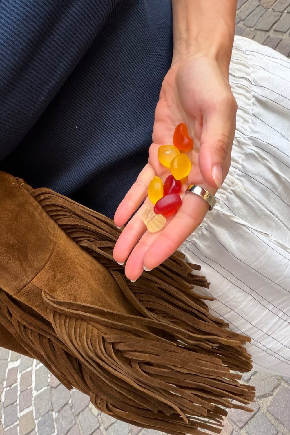 In der Hand von INA KENT liegen mehrere kleine, bunte Gummibonbons in der Handfläche.