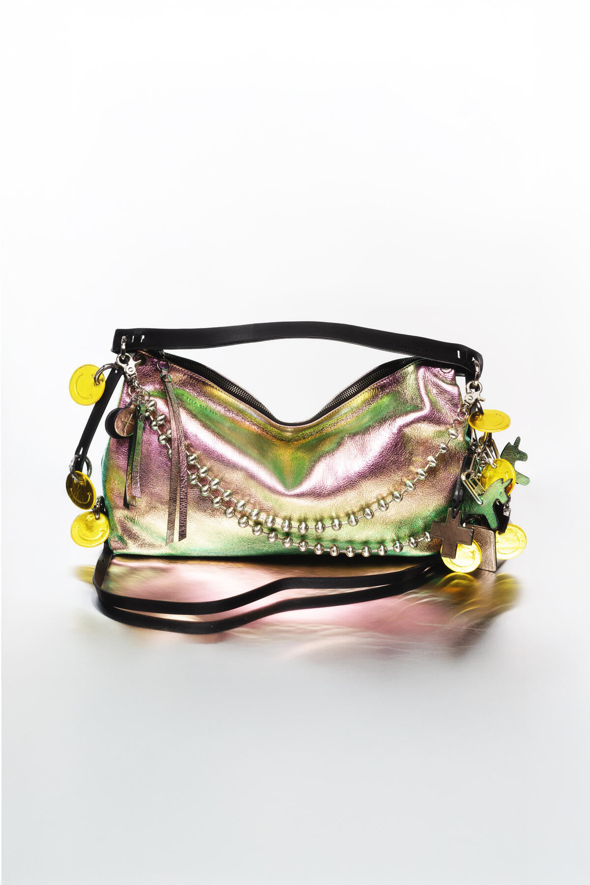 A metallic iridescent INA KENT handbag with black straps, chain and stud details, and yellow round keychains attached to the zippers.
