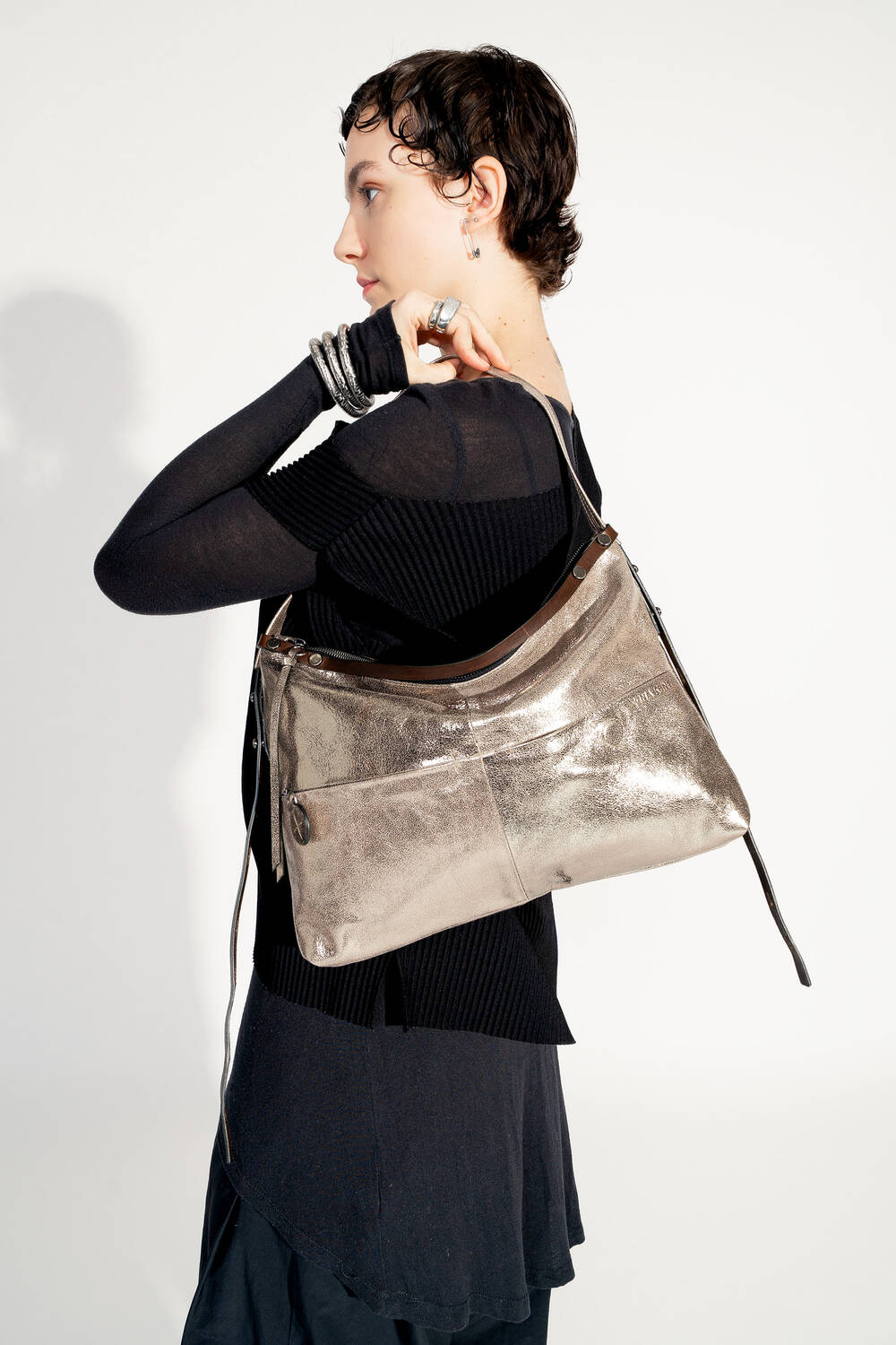 Model mit INA KENT ROVE ed.3 metallic bright anthra (seitlich, Ansicht von hinten): Die Tasche wird seitlich getragen, der Fokus liegt auf der glänzenden Oberfläche und den minimalistischen Details. Das Model präsentiert die Tasche in einem modernen, monochromen Stil.