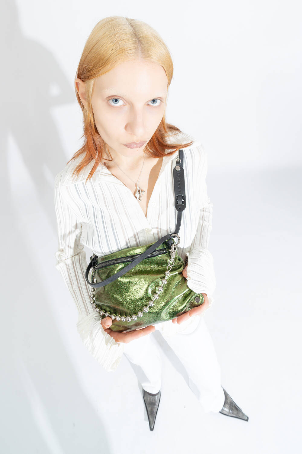 INA KENT bag MOONLIT ed.1 in crackled guacamole is worn diagonally across the chest, combined with a ball chain.