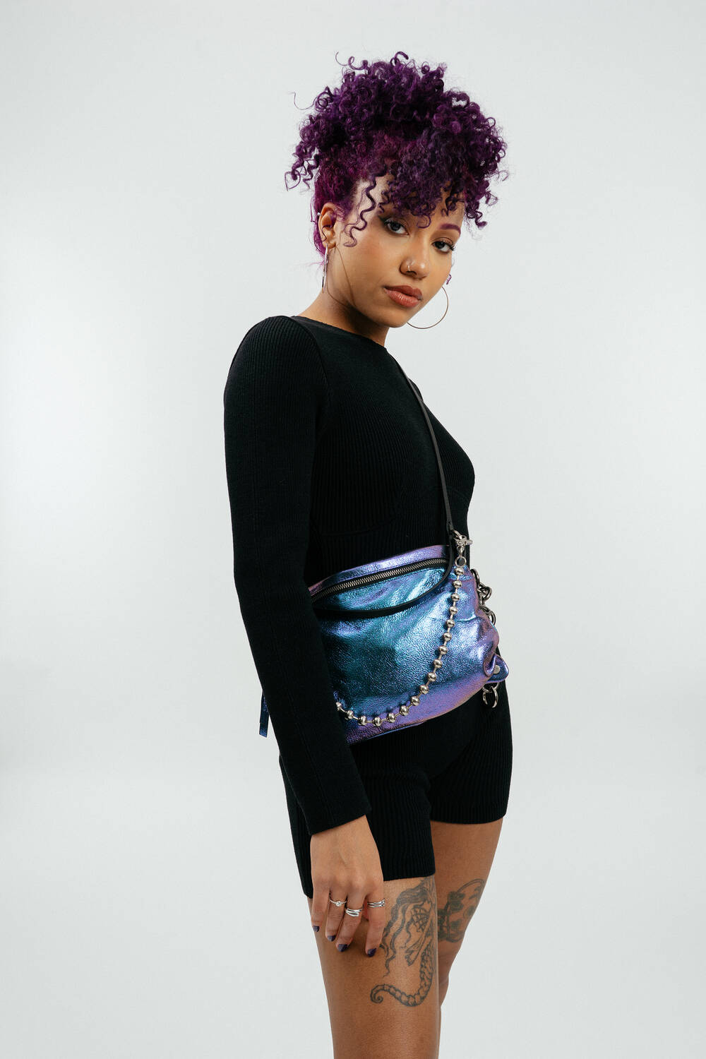 Model in schwarzer Kleidung mit lila-blauen Tasche mit einer Silberkette vorne dran