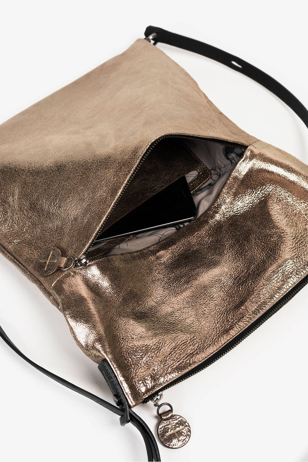 Eine INA KENT Crossbody Bag in Bronze-Metallic mit einem teilweise geöffneten Reißverschluss, der ein schwarzes Smartphone im Inneren offenbart.