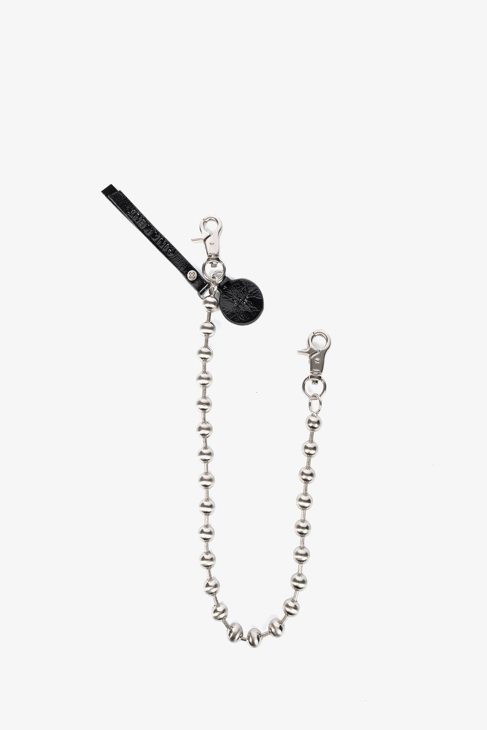 A silver beaded keychain by INA KENT with two lobster clasps, a black leather tag, and a round black charm, displayed on a white background.