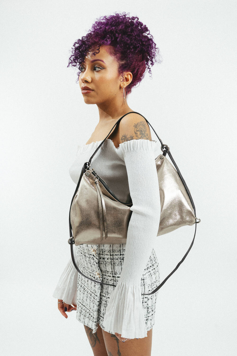 Weiblich gelesene Person mit goldener Tasche mit schwarzem Riemen am Rücken