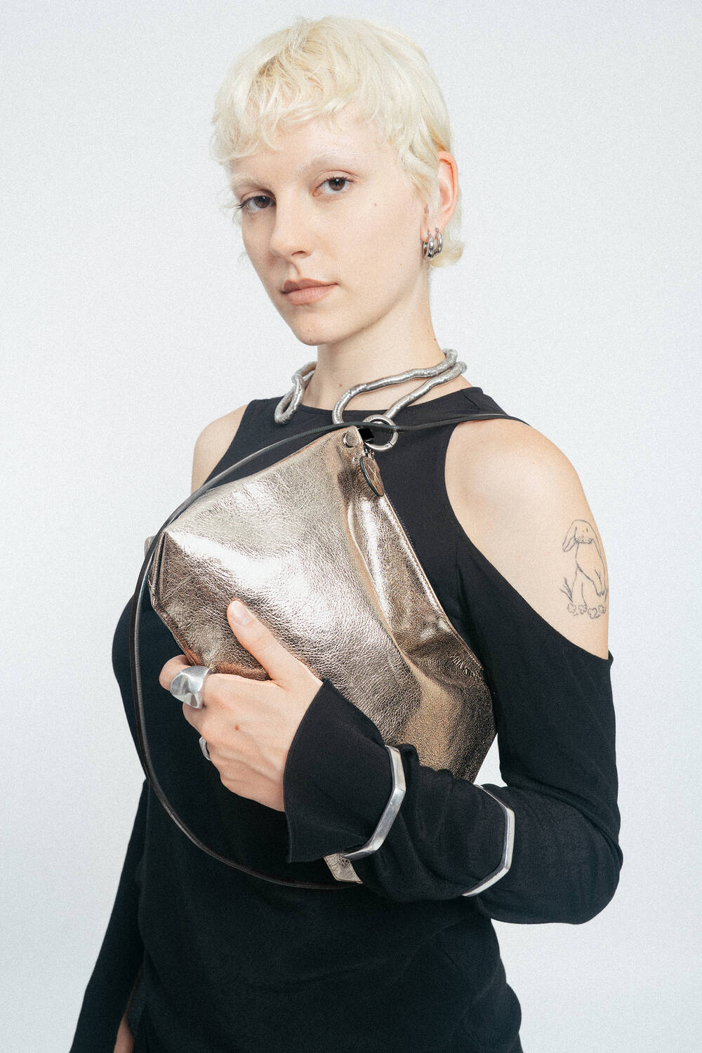 Weiblich gelesene Person mit goldener Tasche mit schwarzem Riemen