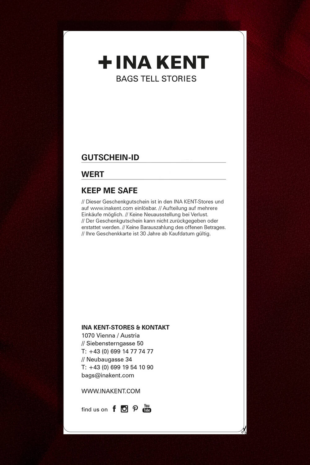 A rectangular INA KENT gift card features the brand’s store details, terms, and contact information printed in black on a crisp white background.