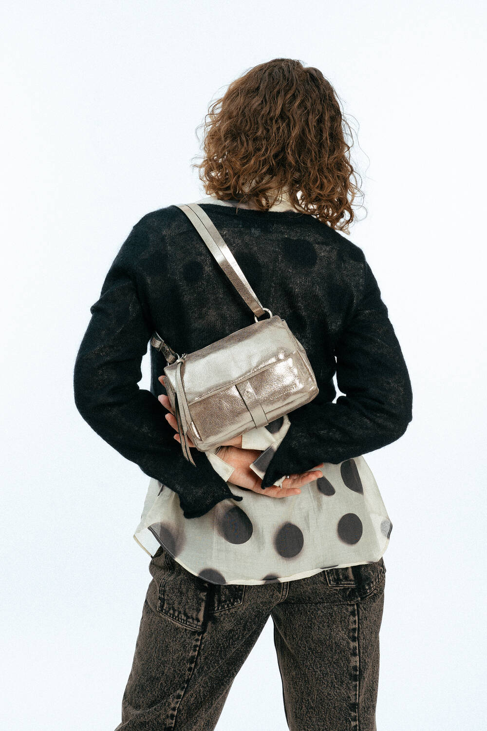 Weiblich gelesenes Modell mit goldener Tasche auf der Schulter