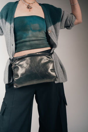 Vom Model ist nur die Körpermitte bis zu den Beinen zu sehen; die Frau trägt eine INA KENT Hüfttasche MOONLIT ed.1 aus Metallic-Leder in grau