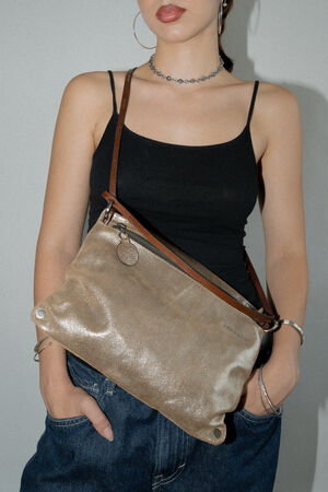 A person wearing a black tank top and blue jeans carries an INA KENT tan leather crossbody bag.