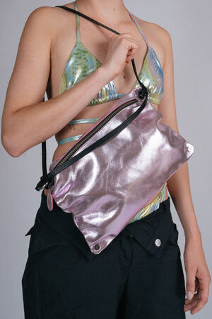 Person wearing a green and blue patterned bikini top and black pants, holding an INA KENT metallic pink shoulder bag with a black strap.