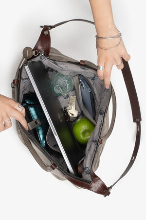 Open INA KENT handbag revealing its contents, including a laptop, a green apple, keys, a wallet, a water bottle, and a phone. Two hands hold the bag open.