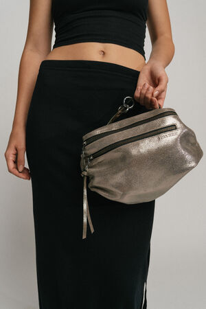 A person is holding a metallic silver INA KENT bag while wearing a black skirt and a black top.