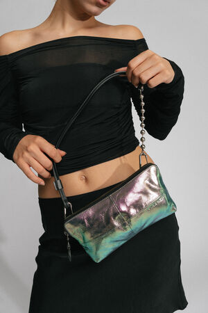 A person wearing a black off-the-shoulder top and black skirt holds a small, metallic INA KENT handbag with a short strap.