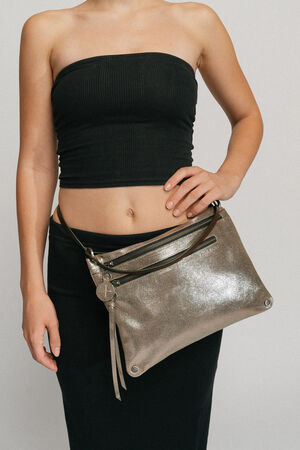 A woman wearing a black tube top and skirt holds an INA KENT metallic silver clutch with a strap slung across her torso.