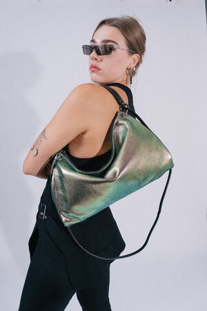 A person wearing sunglasses, a black outfit, and a tattoo on their arm holds an INA KENT metallic green handbag over their shoulder.