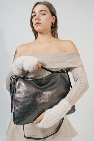 Person in an off-shoulder beige sweater holding a large metallic INA KENT handbag.