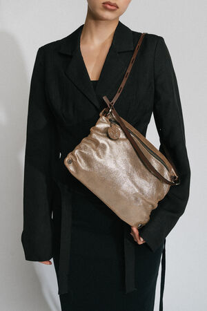 Dressed in black, the individual carries an INA KENT metallic gold handbag with a shoulder strap.