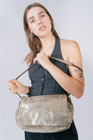 A person with long hair wears a sleeveless top and holds an INA KENT metallic shoulder bag in front of their chest.