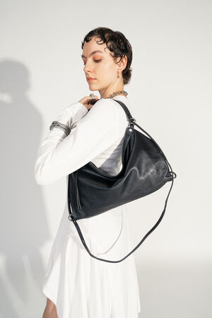 INA KENT DINKUM ed.2 natural true black (sideways, worn): The bag is worn by one person on the shoulder. The minimalist black design and the smooth leather surface really come into their own.