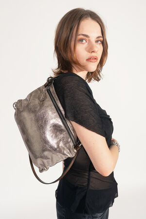 Female read person carries the INA KENT MOONLIT ed.1 bag in metallic bright anthra under the shoulder (short). The shiny bag hugs the back and has an adjustable strap.