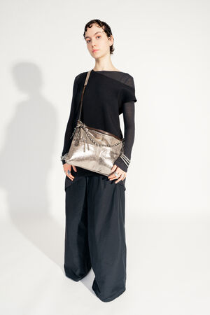 Model with INA KENT ROVE ed.3 metallic bright anthra (slanted, worn from the side): The bag is worn over the shoulder and shows off its clear shape and shimmering surface. The model is wearing an elegant black outfit.