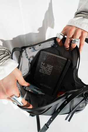 Offene Ansicht der Tasche DINKUM ed.2 in natural true black. Der Innenraum der Tasche zeigt ein praktisches Fächersystem und enthält ein Smartphone sowie ein Notizbuch.