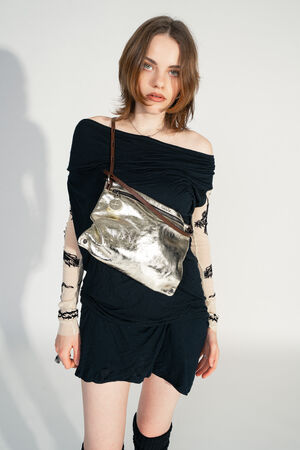 The MOONLIT ed.1 by INA KENT is worn crossbody, the soft metallic silver leather reflects the light. The brown strap sits loosely, while the model looks into the camera with a confident, gentle gaze.