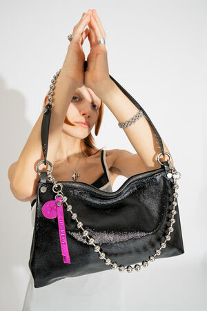 INA KENT Tasche ORNAMENT ed.2 in patent ink black, präsentiert. an erhobenen Händen, betont mit der markanten Metallkugel-Kette