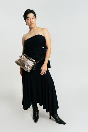 Person standing against a plain background wearing a strapless black dress, black boots, and an INA KENT metallic crossbody bag.