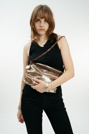 A woman with shoulder-length brown hair wears a black sleeveless top and holds an INA KENT metallic crossbody bag against a plain white background.