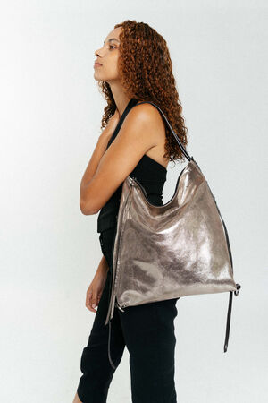 Weiblich gelesene Person mit beutelnder goldener Tasche mit schwarzen Riemen 