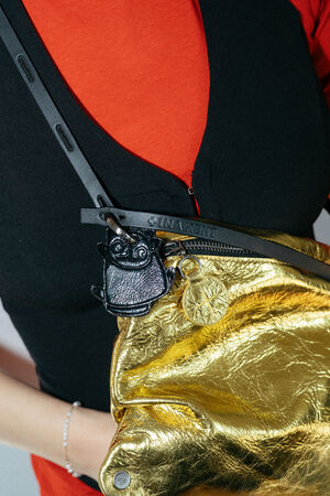 kleiner, schwarzer Anhänger in Katzenform aus Leder an gelber Ledertasche