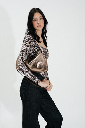 Weiblich gelesenes Model mit dunklen Haaren trägt goldene Ledertasche auf der Schulter