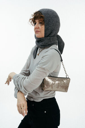 Weiblich gelesenes Model mit kleiner goldenen Ledertasche auf der Schulter