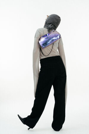 Weiblich gelesenes Model mit lila-blauen Tasche auf der Schulter