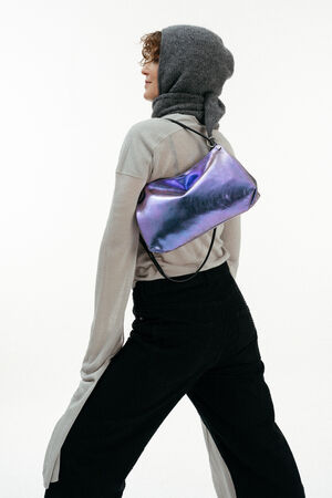 Weiblich gelesenes Model mit lila-blauen Tasche auf der Schulter