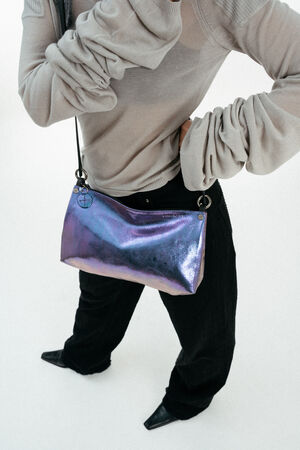 Weiblich gelesenes Model mit lila-blauen Tasche Crossbody