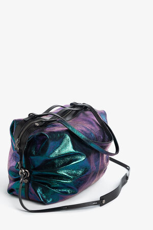 Schillernde teal- und lilafarbene INA KENT Handtasche mit schwarzen Lederriemen und einem Reißverschluss, fotografiert vor einem schlichten weißen Hintergrund.
