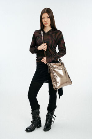 weiblich gelesenes Model mit goldener, großen Ledertasche Crossbody getragen