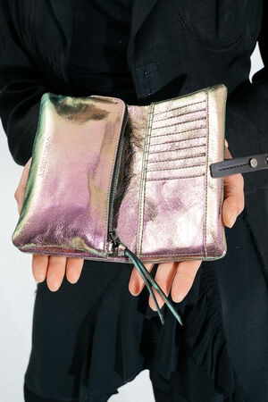 Person holding an open, iridescent metallic INA KENT wallet with a zippered compartment and several card slots, against a plain background.