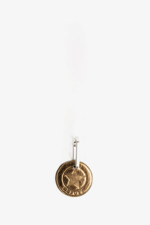 A gold oval keychain by INA KENT with a raised star and the word "DESIRE" engraved on it, attached to a metal keyring, set against a plain white background.