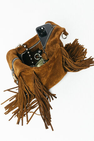 An INA KENT brown suede fringe handbag with a phone, keys, and jewelry partially visible inside.