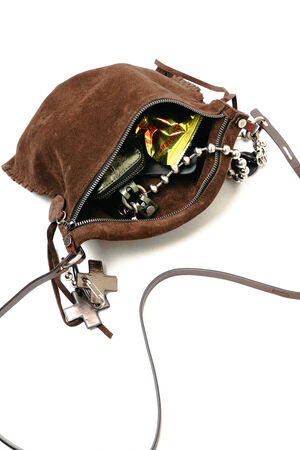 A small brown suede INA KENT bag with a shoulder strap, unzipped to reveal a metallic wallet, a yellow snack wrapper, a beaded bracelet, and keys inside.