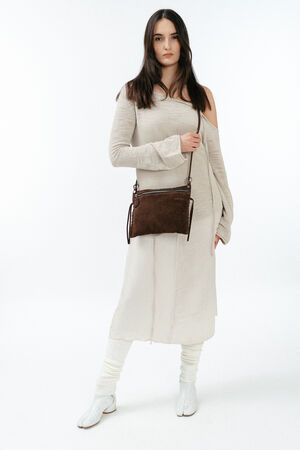Woman standing against a white background wearing a beige long-sleeve dress, white boots, and carrying an INA KENT brown crossbody bag.