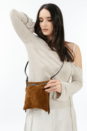 A woman in a light beige off-shoulder sweater holds an INA KENT brown suede crossbody bag with a black strap against a plain white background.