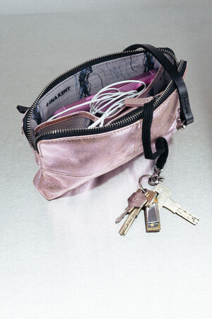 A small pink INA KENT zippered pouch with keys attached to a strap; inside are visible cables and a glasses case.